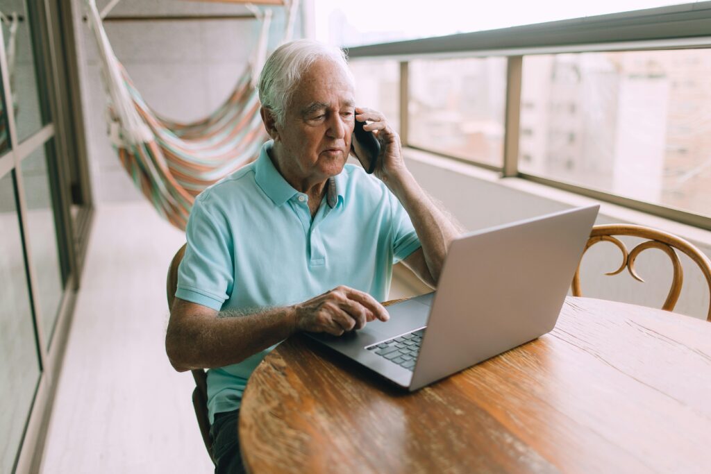 A man on the phone with a computer in front of him.