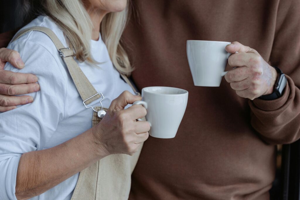 A couple holding mugs drinking coffee.